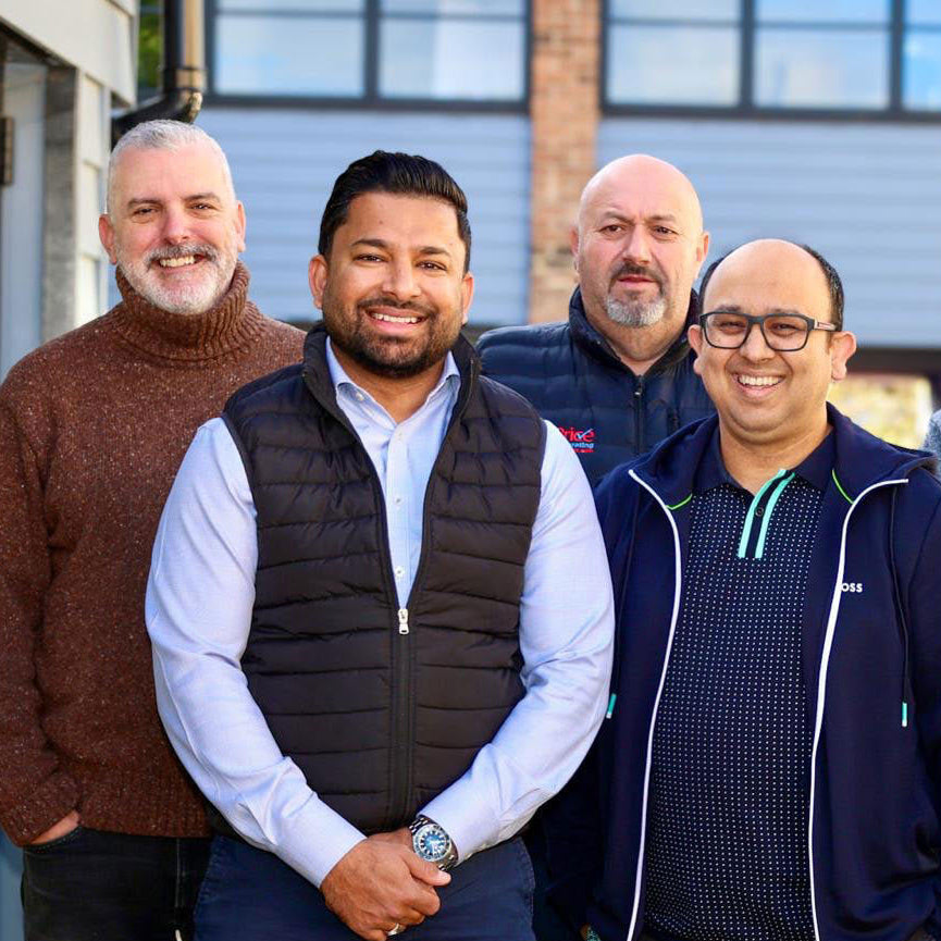 Four men posing together outdoors with a building in the background