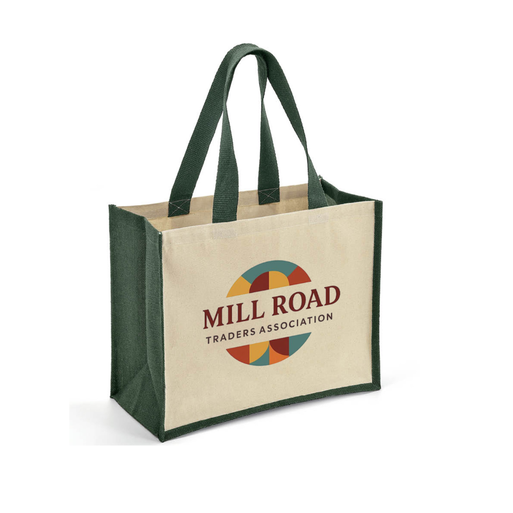 A canvas tote bag with dark green handles and side panels, featuring a printed 'Mill Road Traders Association' logo on the front, set against a plain white background.