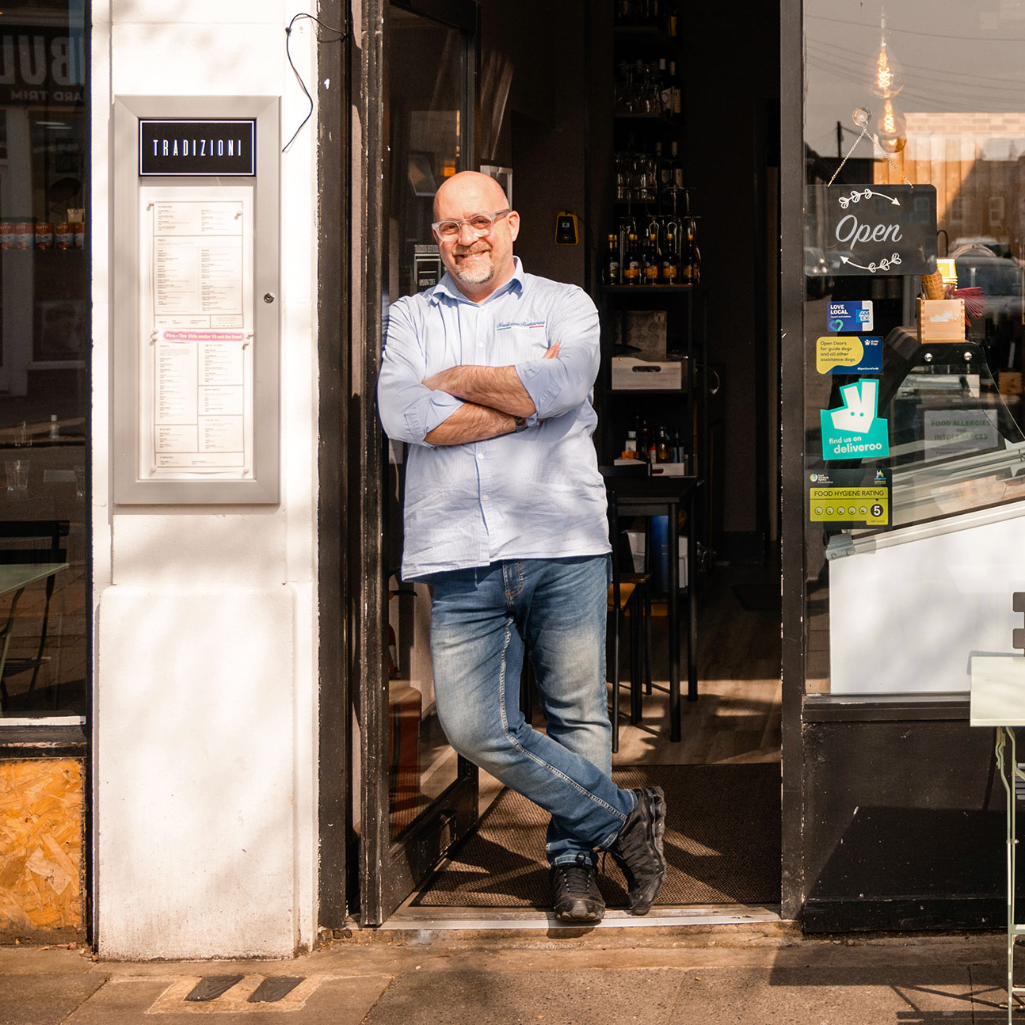 man standing in front of a restaurant entrance