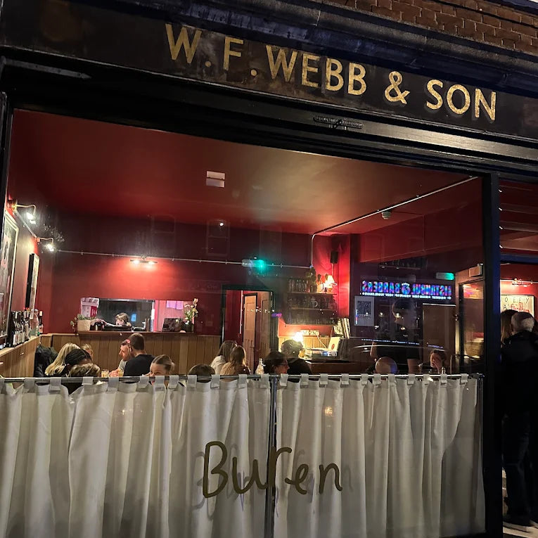 Establishment with 'W.F. Webb & Son' sign and people gathered outside.