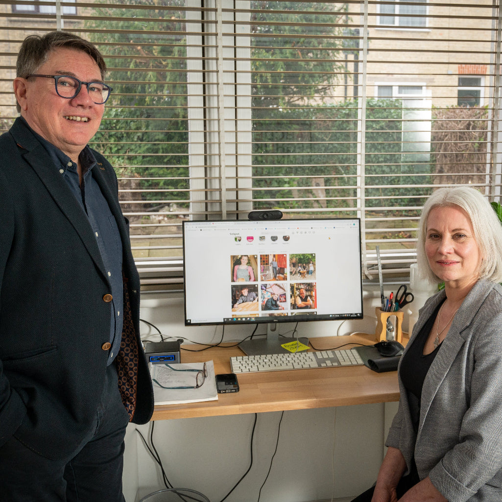 2 people sitting infront of a desk ad computer