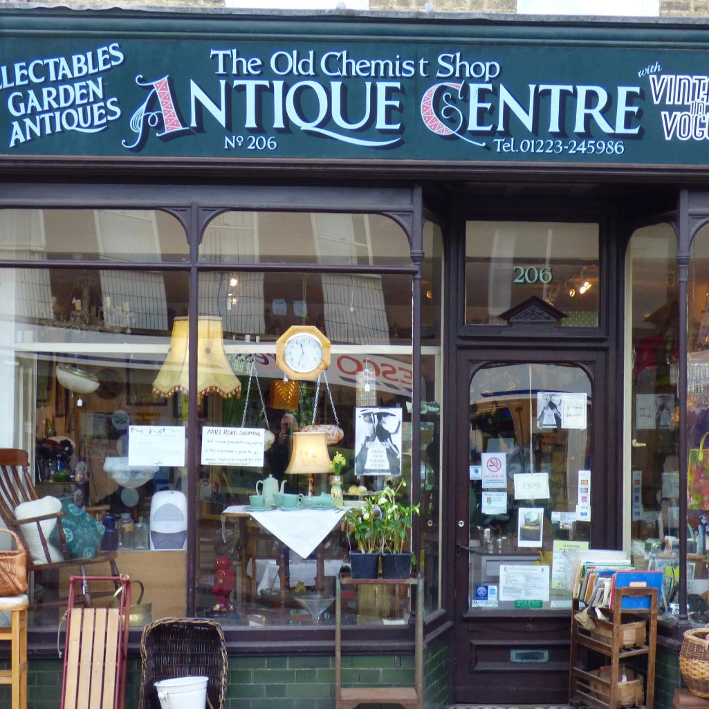  storefront of 'The Old Chemist Shop Antique Centre' with various items displayed inside.
